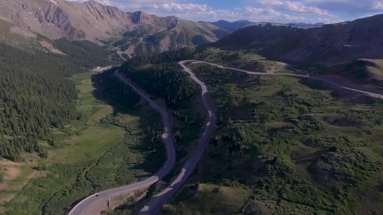 Cars driving over high elevation winding rocky mountain pass drone 4k