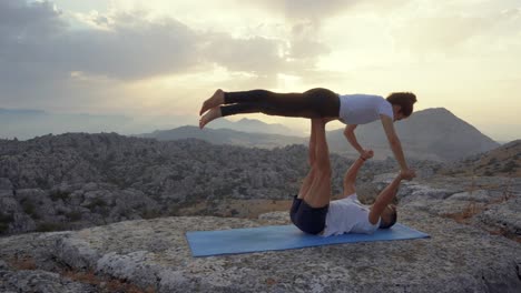 couple practicing acro yoga in nature