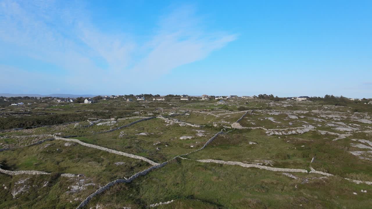 casas de granjeros en connemara cerca de la playa de coral strand con campos divididos por paredes hechas de rocas bajo el cielo azul brillante en irlanda