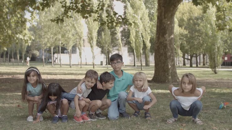 Crianças multiétnicas alegres agachando e se levantando no parque
