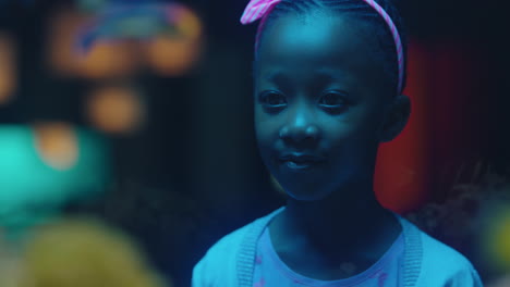 african american girl looking at fish in aquarium curious child watching colorful sea life swimming in tank learning about marine animals in underwater ecosystem inquisitive kid at oceanarium