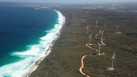 aerial view overlooking a wind farm, at the ocean, in albany, australia - tracking, drone shot