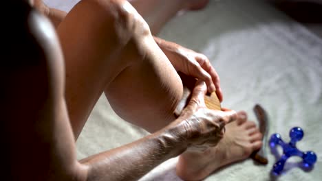 Extreme-overhead-closeup-of-woman-using-a-gua-sha-tool-to-rub-the-muscles-in-her-calf