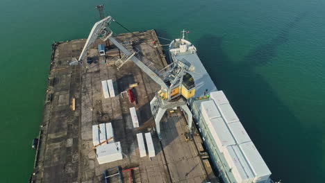 cargo ship docked at the harbor with port crane for loading of goods