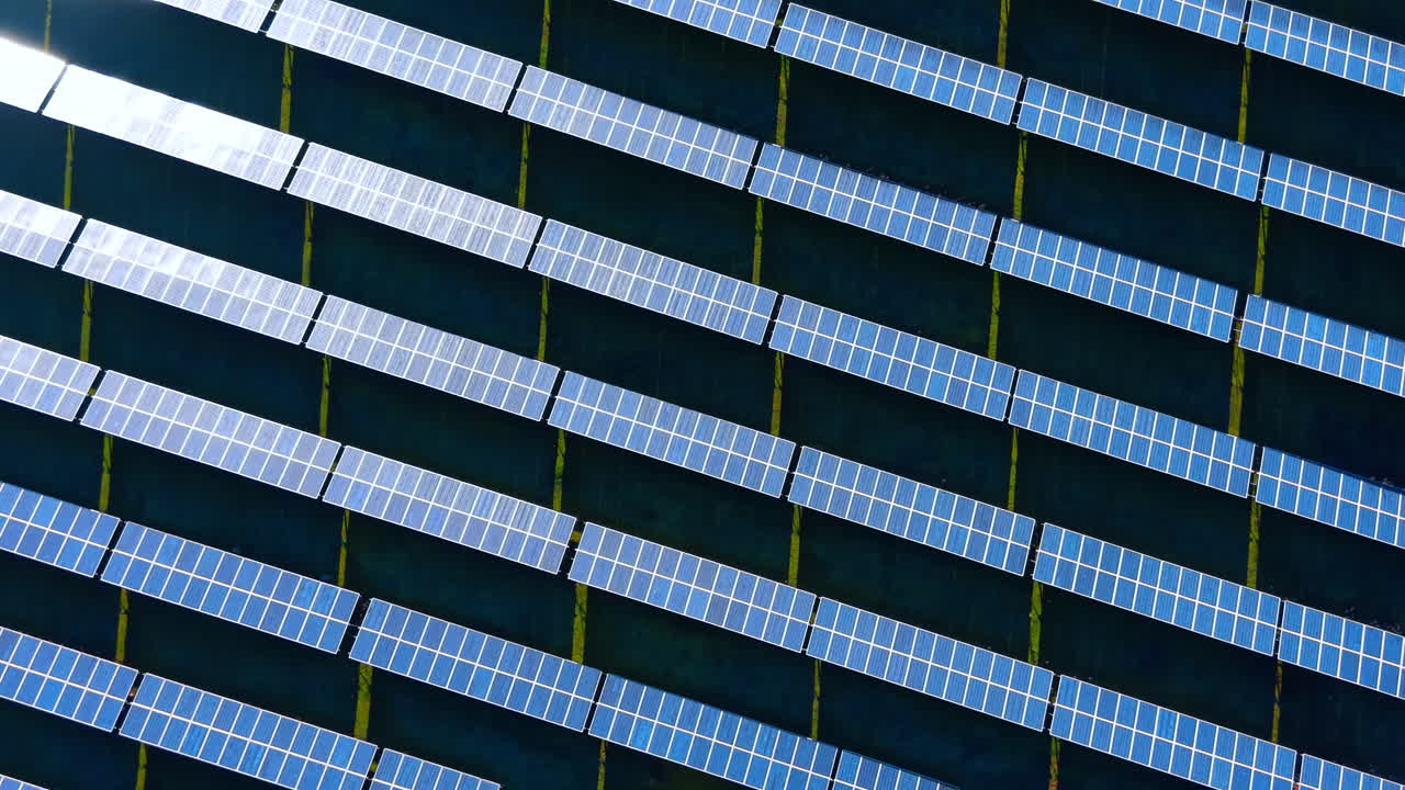 Installazione di pannelli solari vista dall'alto con ombre lunghe. Veduta dall'alto di moduli fotovoltaici su campo verde durante il tramonto o l'alba con ombre allungate