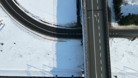 cars moving along the bridge which crosses highway and railroad in winter poland rakowice - daytime drone top-down view slow motion