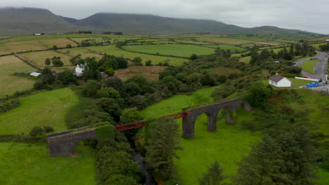 Fly-over-historic-Lispole-viaduct.-Steel-and-stone-construction-of-old-railway-bridge-over-valley.-Tilt-up-reveal-landscape-panorama.-Ireland