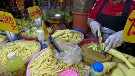 person slicing bamboo shoots at a food stall