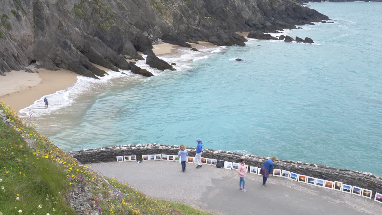 Turisti sulla strada che si affaccia sulla spiaggia di Coumeenoole con scogliere frastagliate e onde dell'oceano