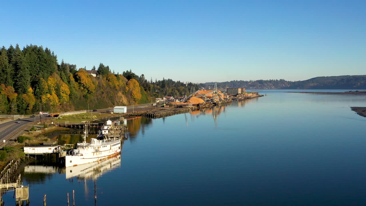 Ripresa aerea lenta in avanti sulla costa dell'Oregon, grande nave e segheria distante