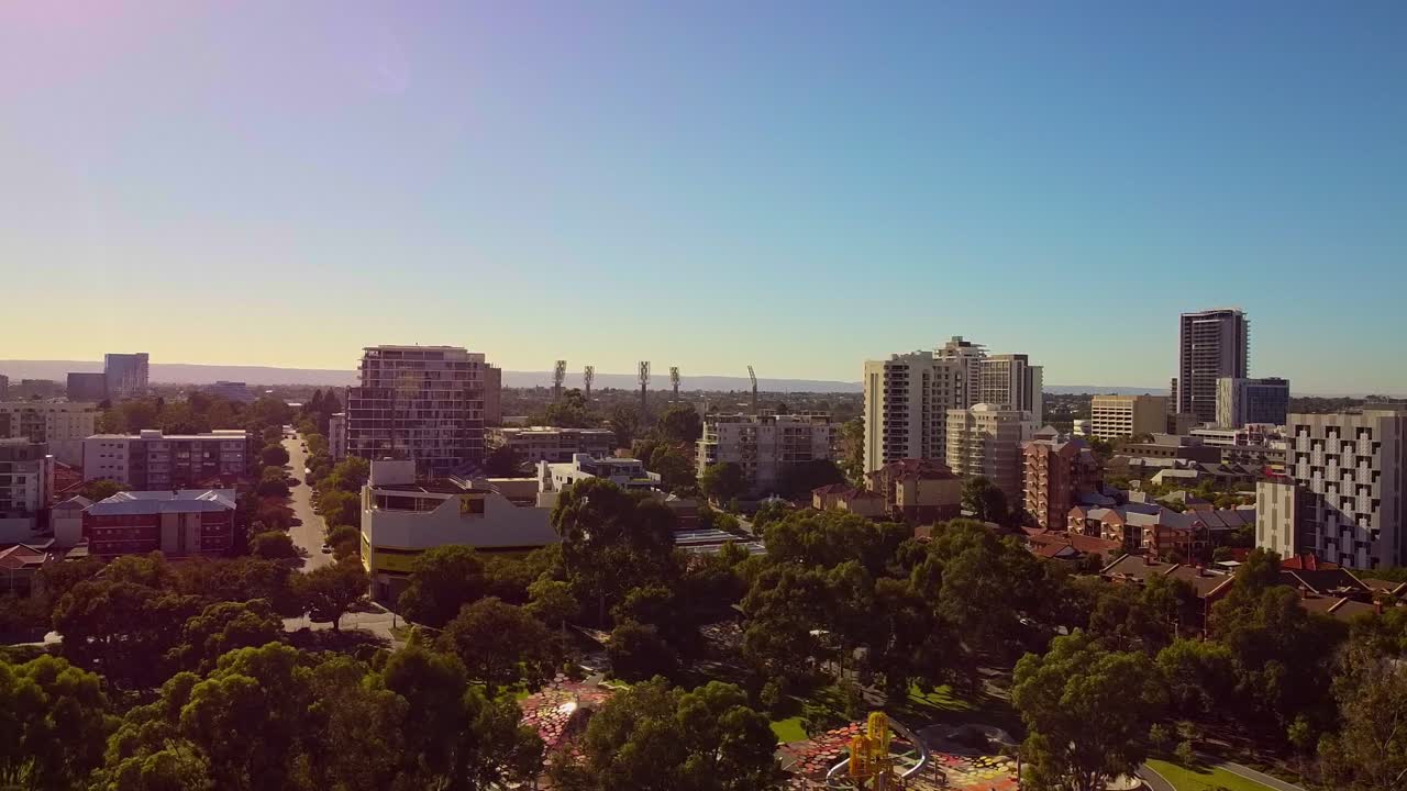 dolly aéreo dejado sobre las copas de los árboles con edificios de east perth y colorido amanecer