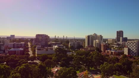 aerial dolly left over treetops with east perth buildings and colourful sunrise