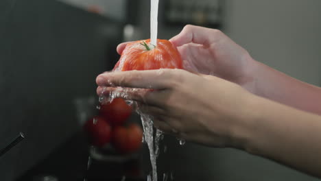 Las-Manos-De-Las-Mujeres-Lavan-Un-Tomate-Con-Agua-Corriente.-Vídeo-En-Cámara-Lenta-4k