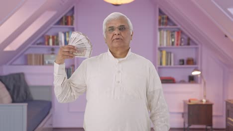 anciano indio usando dinero como ventilador