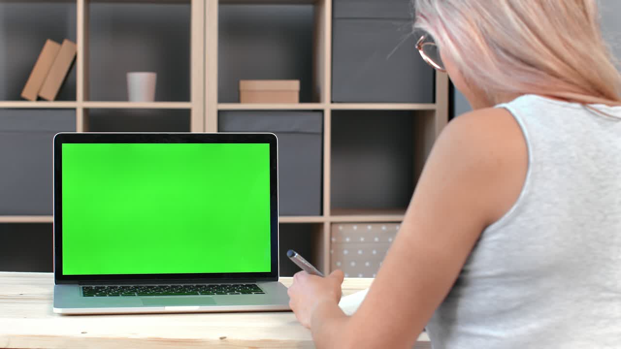 vista trasera estudiante mujer estudiando e aprendiendo tomando notas en la pantalla verde de la computadora portátil educación a distancia