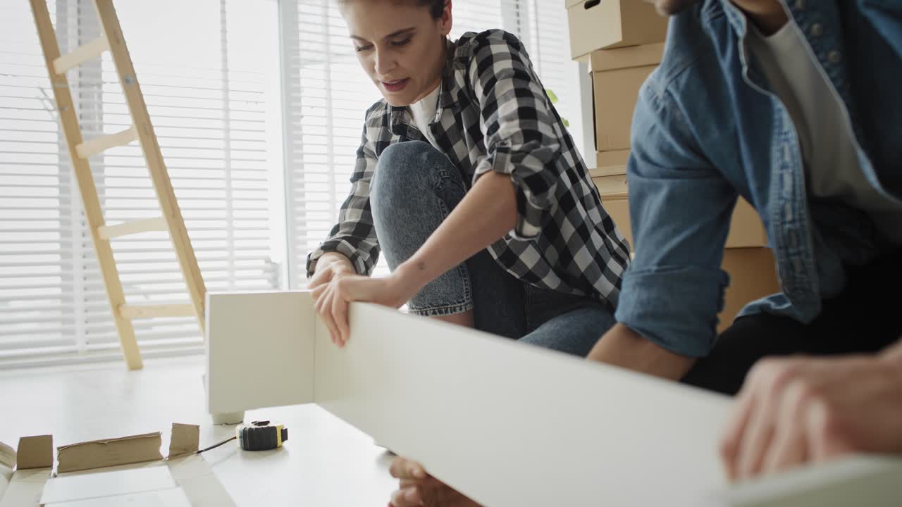 video de mano de una pareja instalando una estantería para una casa nueva.