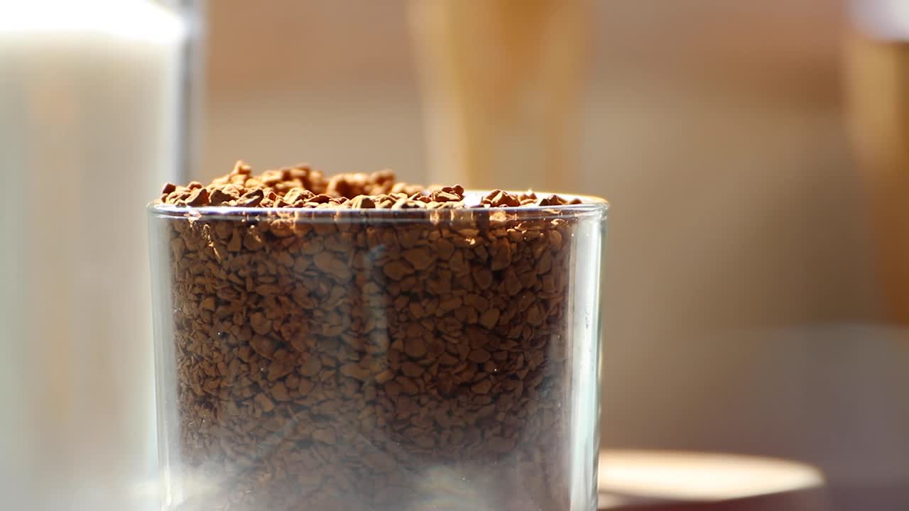 Teaspoon scooping coffee granules from glass jar