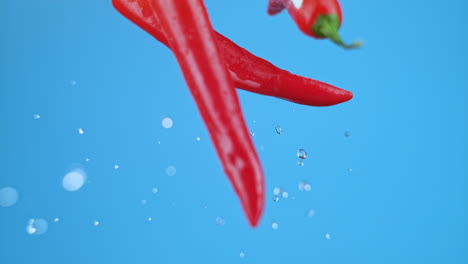 Three-large-red-bell-peppers-launched-in-air-with-water-droplets,-fresh-cooking-ingredients-flying