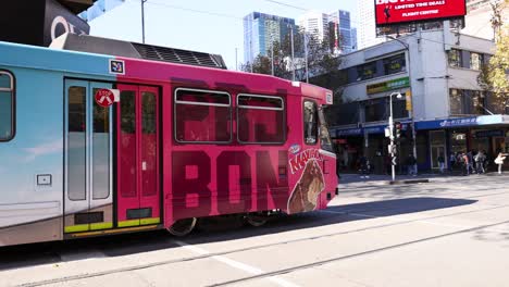 un tranvía se mueve a lo largo de una concurrida calle de melbourne