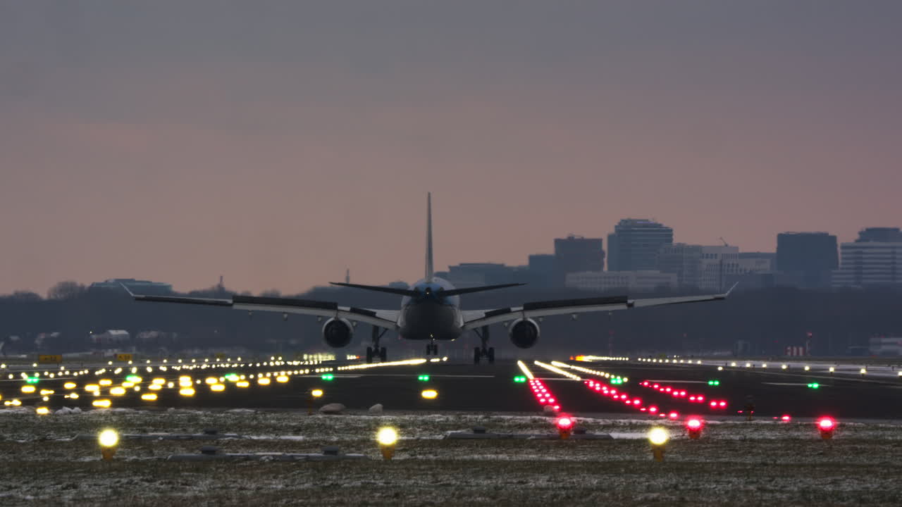 Grande aereo passeggeri in atterraggio su pista illuminata al crepuscolo.