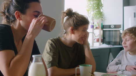 little boy talking with lesbian parents during meal at home