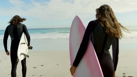 Couple-with-surfboard-walking-on-the-beach-4k