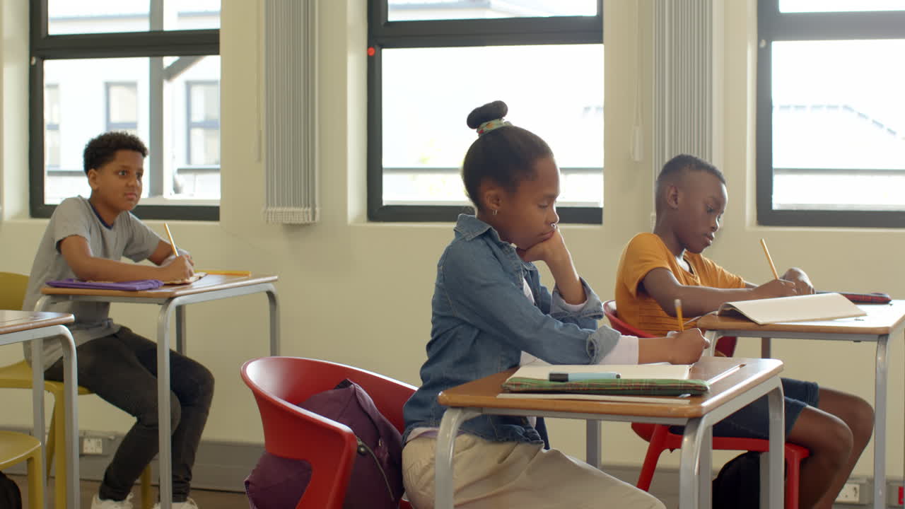 In classroom, multiracial students focused on writing assignments at desks, at school