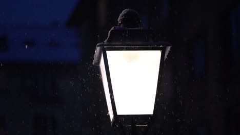 luz de la calle europea en la noche mientras la nieve cae pacíficamente a su alrededor