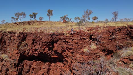 isolated man sitting on rocky edge of mountain and admiring panorama in western australia desert