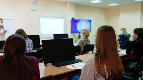 Female auditory attending lecture on ophthalmology. Students sit at the desks in front of computer screens.