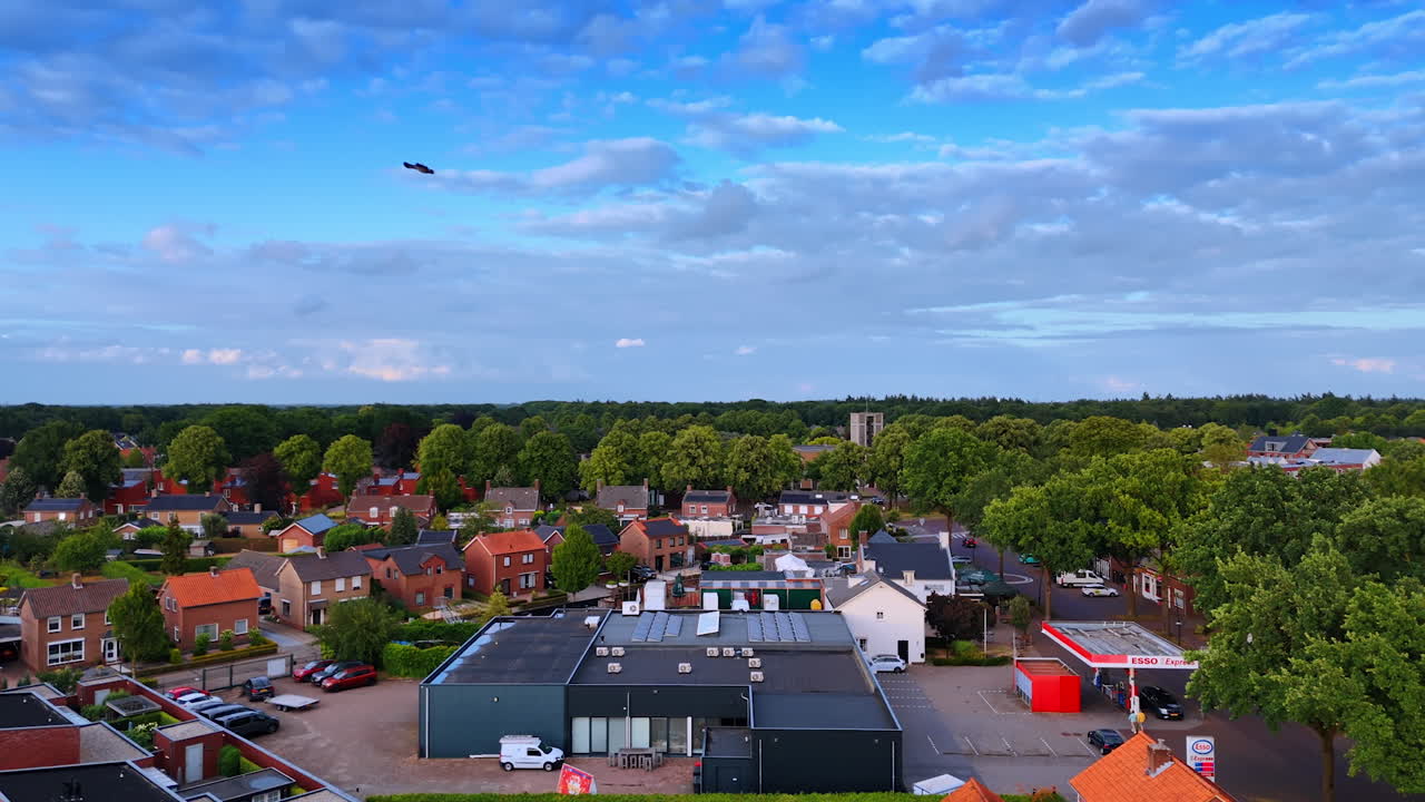 Residential area surrounded by gorgeous green forests. Amazing blue sky with beautiful clouds is over the town