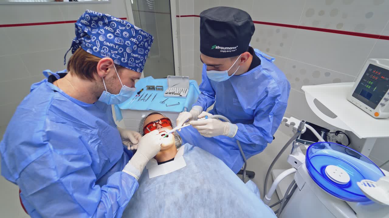 Patient during dental surgery. Male dentist in uniform performing dental surgery