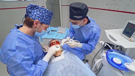 patient during dental surgery. male dentist in uniform performing dental surgery