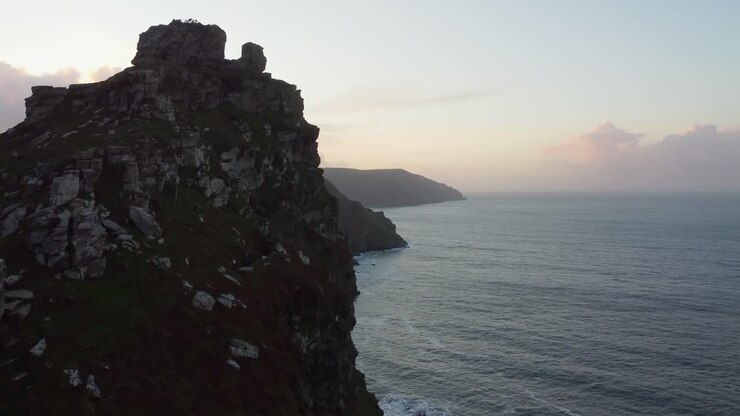 Vista del tramonto nell'ora d'oro lungo la costa con mare calmo e cima di montagna - Filmato aereo con drone.