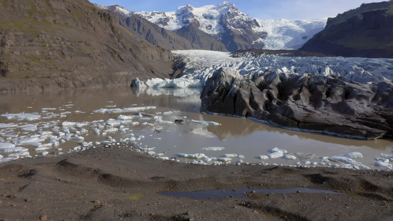 antena: hacia atrás revela la toma de un hombre parado en una colina cerca del glaciar svinafellsjokull durante un día soleado