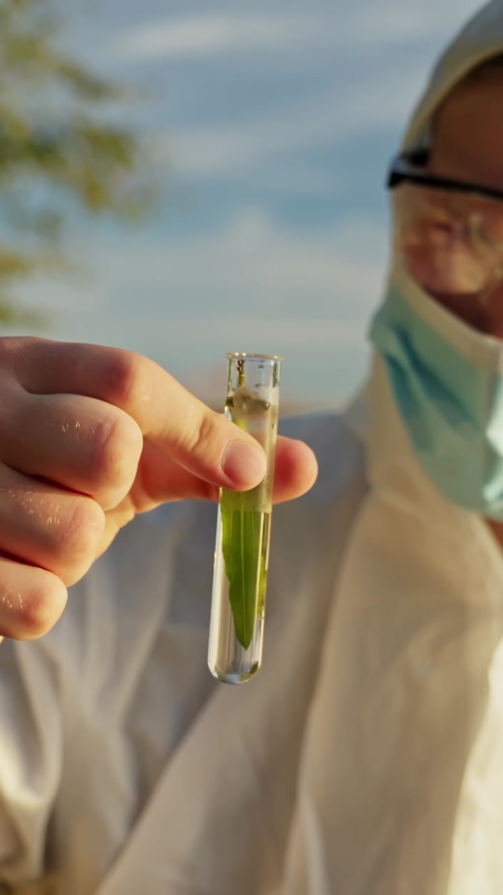 Environmental scientist holding a test tube with a plant specimen for research, closeup vertical shot