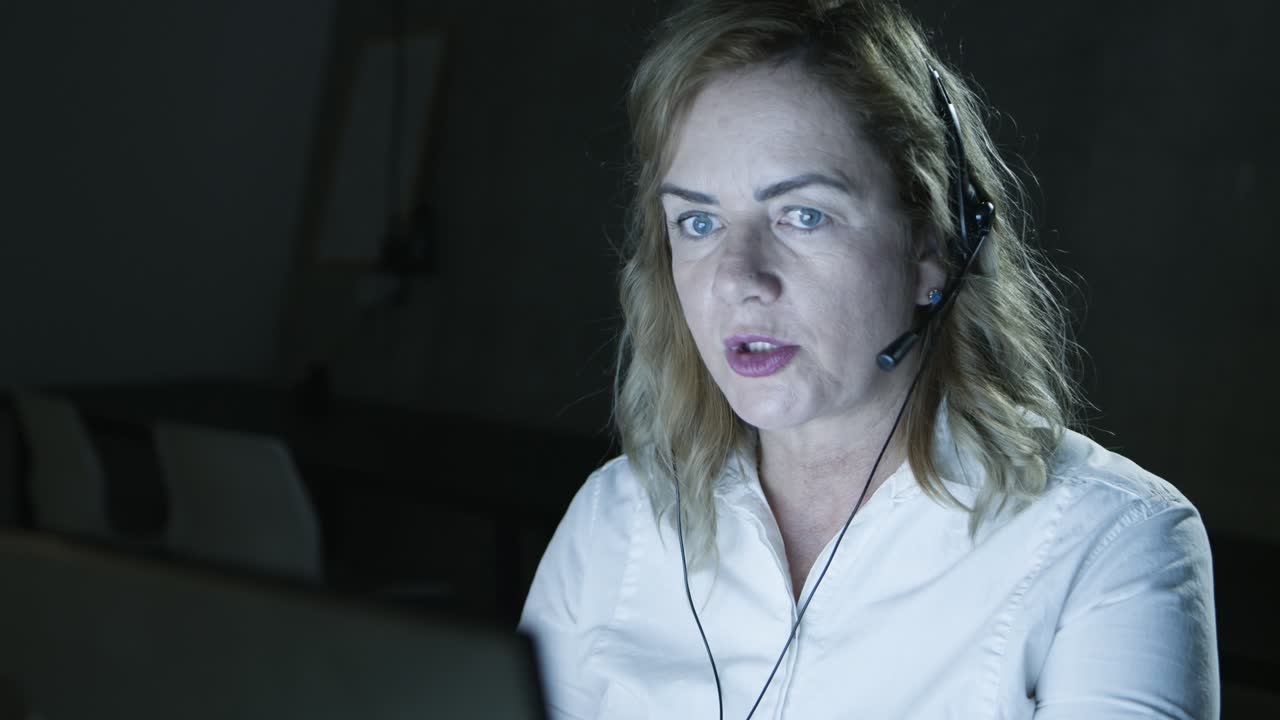 телеработник, отвечающий на звонки в темном офисе