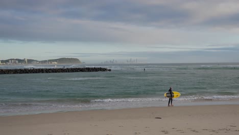 surfer with surfboard walking on the shore of currumbin beach - surfing - gold coast, queensland, australia