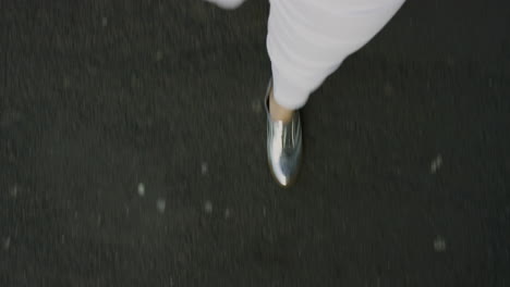 woman-walking-on-asphalt-road-wearing-stylish-silver-shoes-strolling-casual-in-city-above-view