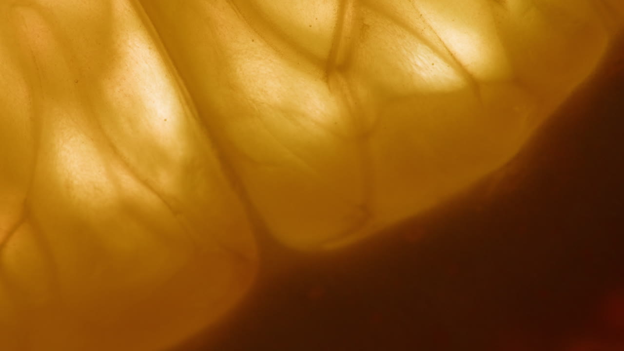 Glowing Citrus Fruit Segment Submerged in Liquid, Macro View