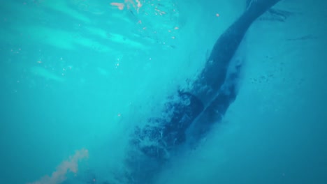 Underwater-view-of-athletic-man-diving-in-the-swimming-pool