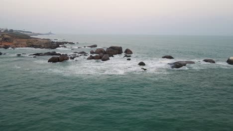 high-altitude aerial drone shot of kanyakumari featuring the city and ocean meeting at dusk.