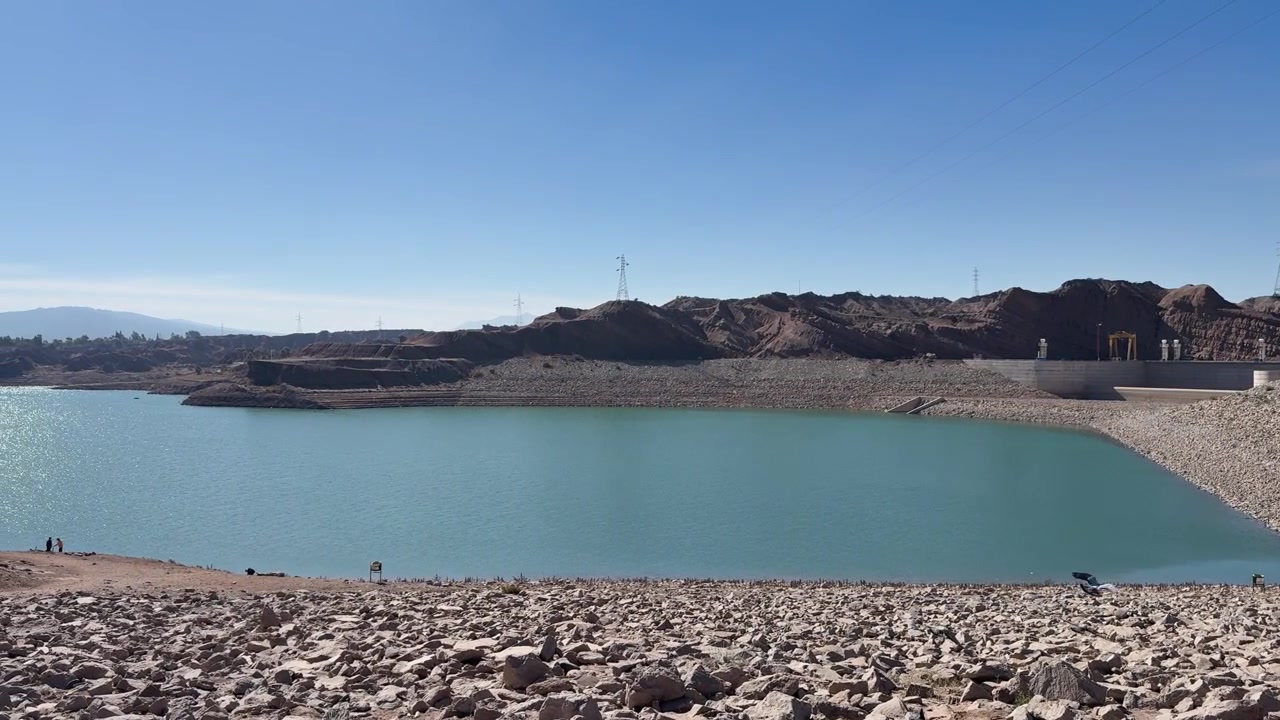 Waduk Dique Ullum di samping tanggul berbatu dan perbukitan gersang di San Juan, Argentina, menampilkan panorama.