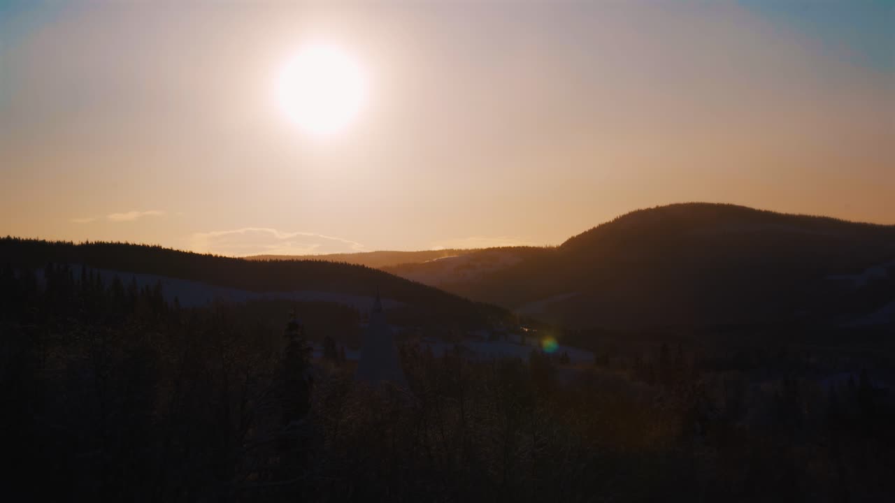 hermosa luz solar naranja en el cielo sobre la silueta de la cordillera nevada en noruega - plano general