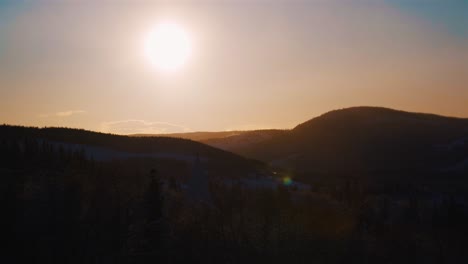 Beautiful-orange-sunlight-at-sky-over-snowy-mountain-range-silhouette-in-Norway---Wide-shot