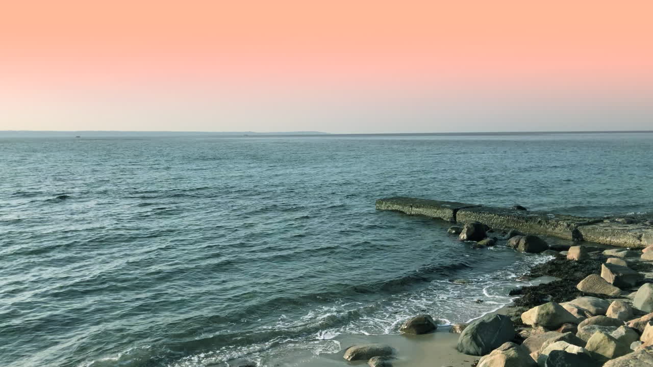 분홍색 하늘 아래 해변에 있는 바위