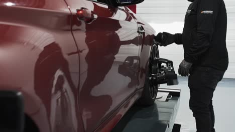 a mechanic clamping on sensors to the car for inspection