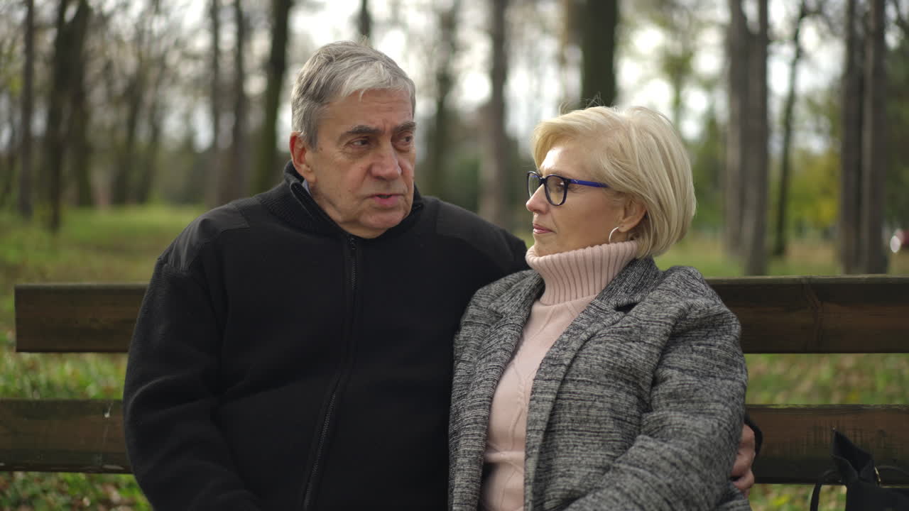 Elderly couple sitting on a bench in the park