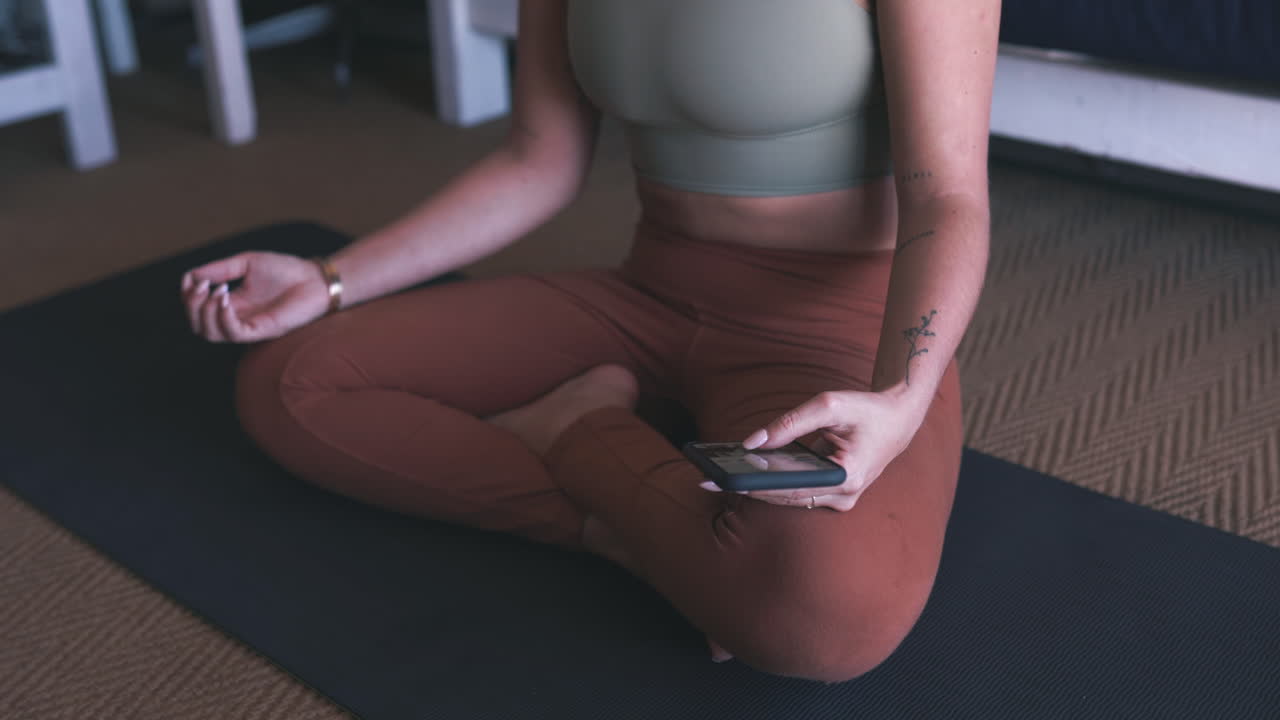 una mujer usando su teléfono celular mientras practica yoga