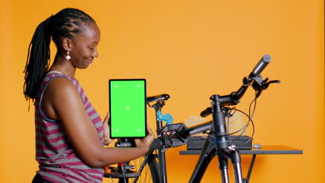 mechanic promoting bicycle fixing service with mockup tablet, studio background